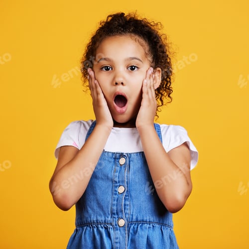 Preview: Studio portrait mixed race girl looking shocked with her hands on her cheeks isolated against a yel