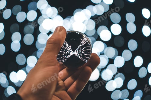 Preview: Person holding a crystal ball reflecting the lights in the background