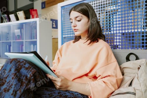 Preview: Concentrating Woman Reading Document on Modern Couch