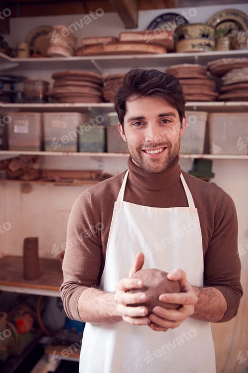 Preview: Portrait Of Male Potter Wearing Apron Holding Lump Of Clay In Ceramics Studio