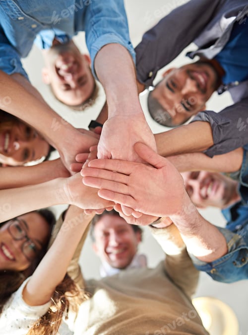 Preview: Low angle shot of a group of co-workers stacking their hands on top of each other