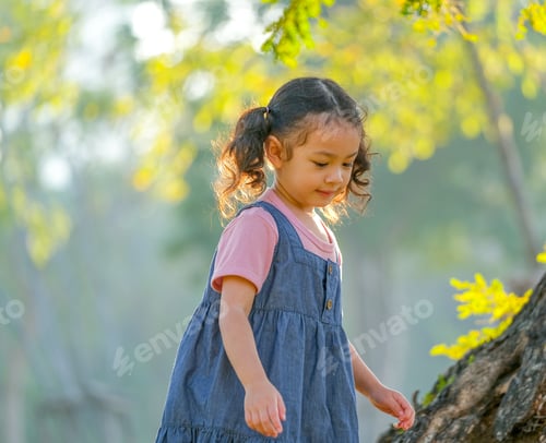 Preview: Young Asian little girl play alone in the garden with morning light.