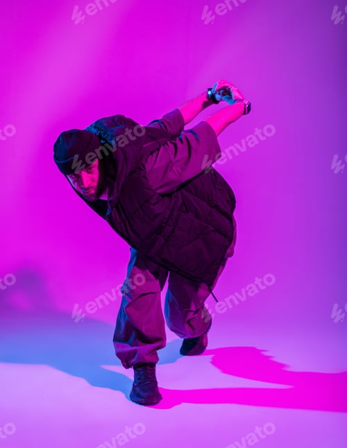 Preview: Stylish dancer guy in trendy clothes dancing in a creative color studio with pink and neon lights