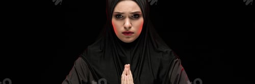 Preview: Portrait of beautiful serious young muslim woman wearing black hijab with hands near her face as
