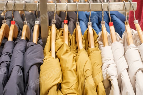Preview: Winter down jackets hanging on hangers in the store close-up, side view.