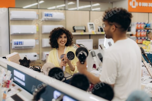 Preview: Young Shoppers in Electronics Store Exploring Hair Dryers Together