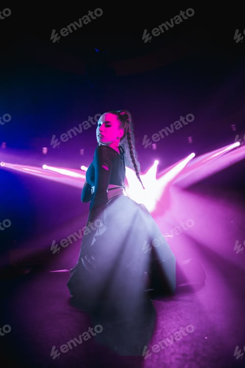 Vista previa: Vertical shot of an attractive woman posing on a club stage with neon lights in the background