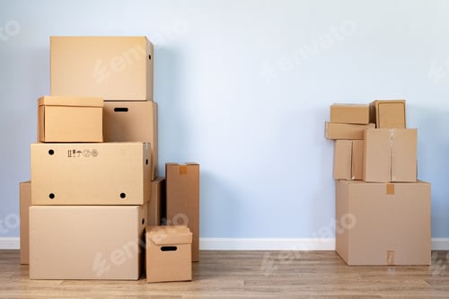 Preview: House moving concept with stacked cardboard boxes in a room