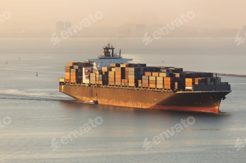 Preview: A large container ship sails through calm waters at sunrise