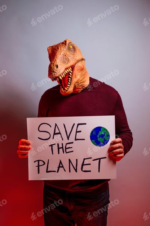 Preview: Man with lizard head in studio holding a cardboard sign that says SAVE THE PLANET