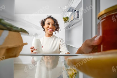 Preview: Young woman opens refrigerator and takes out food