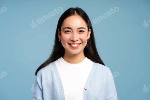 Preview: Smiling Asian woman wearing blue sweater looking at camera standing isolated on blue background