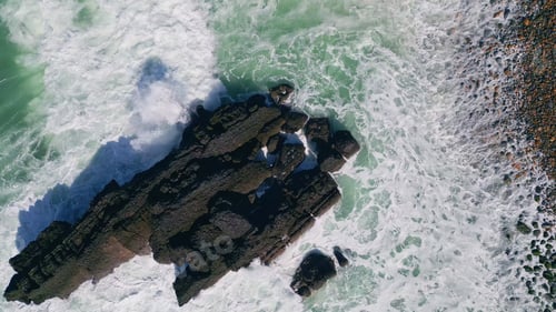 Preview: Top view foaming ocean hitting coastal rock making bubbling foam in slow motion.