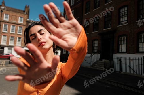 Preview: Young woman protecting herself from sunlight in city street