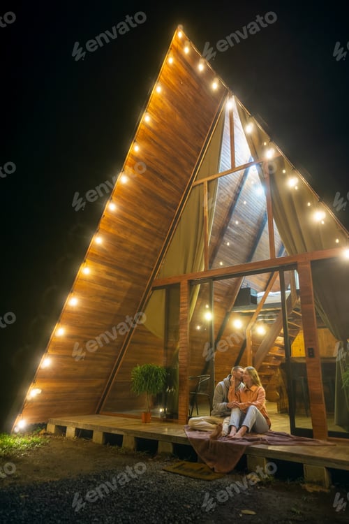 Preview: Couple sitting near the A-frame house in the evening