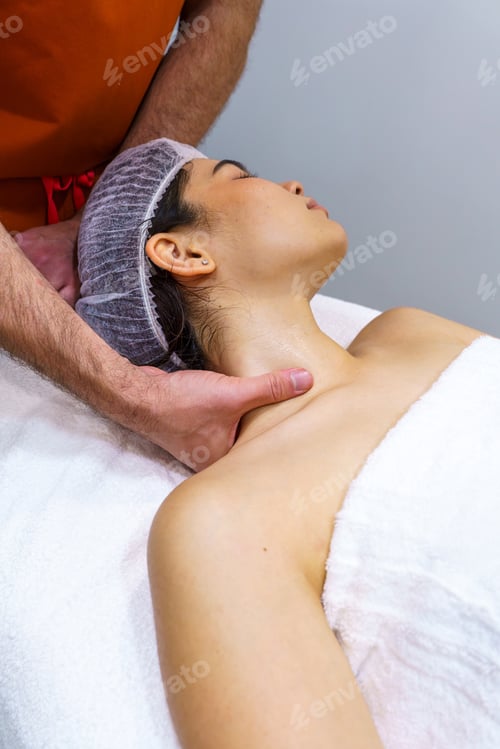 Masajista profesional realizando un masaje de cuello en una mujer joven