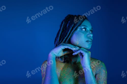 Preview: young and captivating african american woman with dreadlocks, in bright and colorful neon body paint