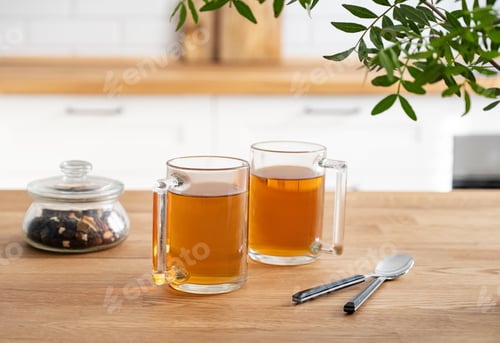 Preview: Two cups of tea with dry flowers on a wooden countertop against the background of a white kitchen