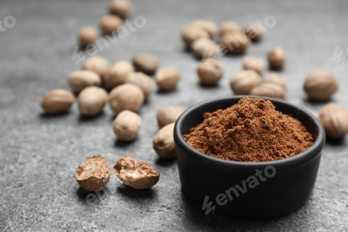 Preview: Bowl of nutmeg powder and seeds on grey table, space for text