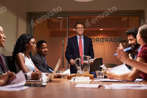 Preview: Smiling businessman addressing team at meeting, low angle