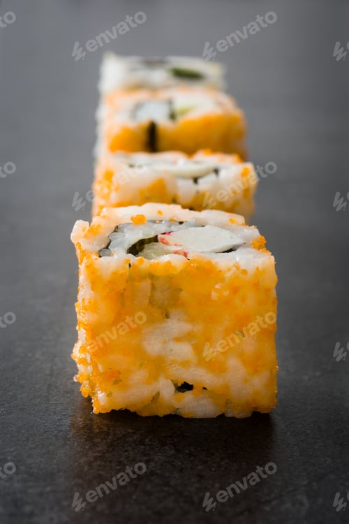Preview: California uramaki sushi rolls with flying fish roe tobiko on dark background