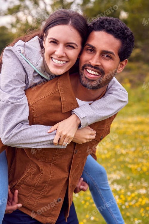 Preview: Portrait Of Couple On Walk In Countryside With a Man Giving Woman Piggyback