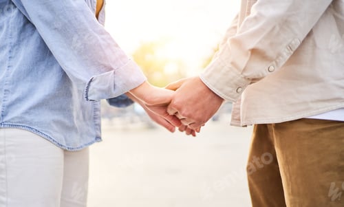 Preview: Beautiful close up photo of two unrecognisable people holding hands outside.