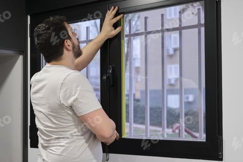 Preview: Man measuring window glass to install frosted window vinyl.