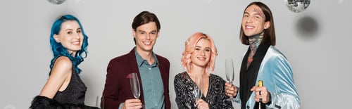 Preview: cheerful queer people with champagne glasses smiling at camera during christmas party on grey
