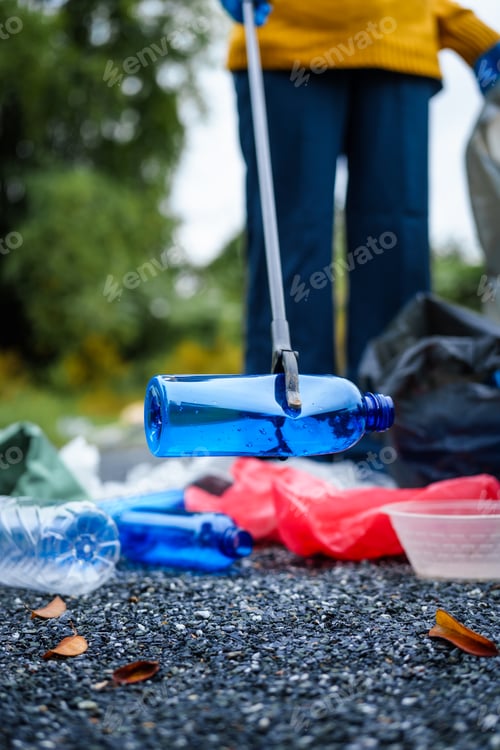 Preview: Close-up of young women girls hands sorting recyclable plastic bottles into trash bags outdoors