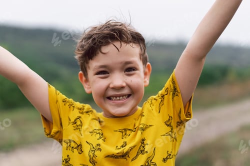 Preview: A six year old boy smiles at the camera in the park