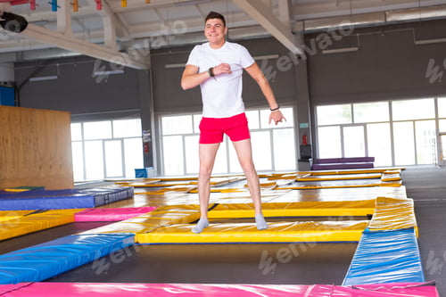Preview: Fitness, fun, leisure and sport activity concept - Handsome happy man jumping on a trampoline