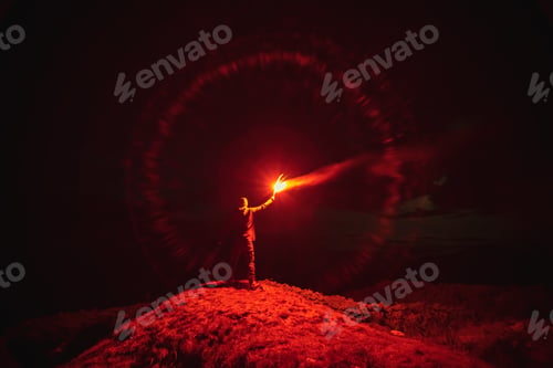 Preview: The man with a red firework stick standing on a mountain. evening night time.