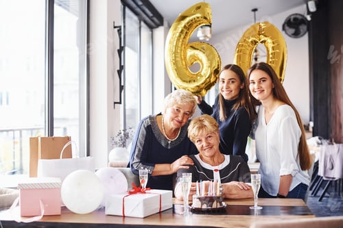 Preview: Balloons with number 60. Senior woman with family and friends celebrating a birthday indoors