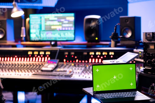 Preview: Young technician recording music on control desk next to mockup laptop