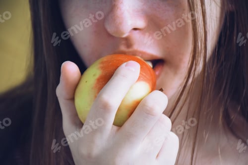 Preview: Young girl is biting an apple