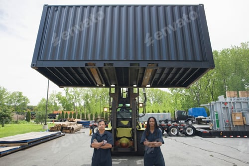Preview: Two workers confidently stand in front of a lifted shipping container at an industrial site.