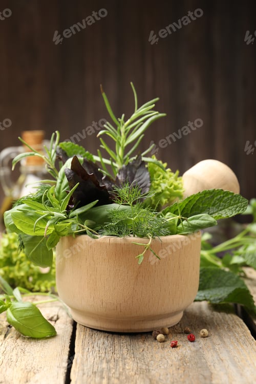 Preview: Mortar with different fresh herbs and peppercorns on wooden table against brown background, closeup