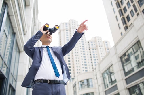Preview: Confident businessman looking through binoculars