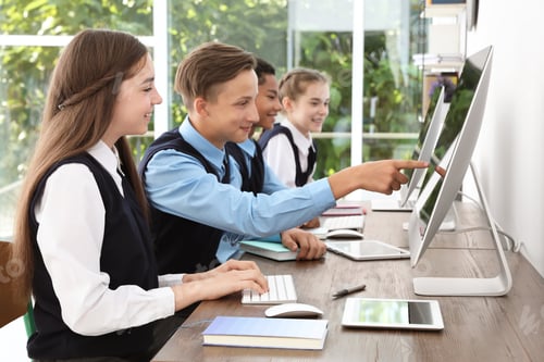 Preview: Teenage students in stylish school uniform at desks with computers