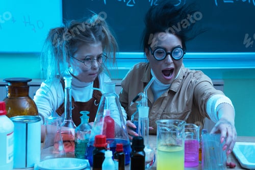 Preview: Teacher and little girl during chemistry lesson mixing chemicals in a laboratory