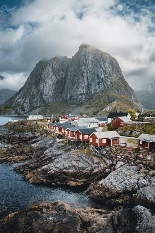 Preview: Vertical shot of a small village surrounded by greenery and rocky mountains in Lofoten, Norway