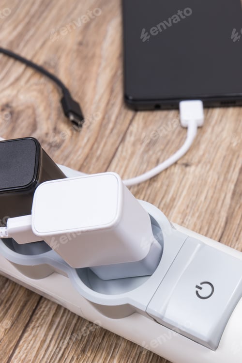 Preview: Smartphone and chargers connected to electrical power strip. Various devices charging concept