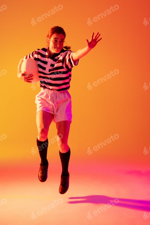 Preview: Caucasian female rugby player with rugby ball over neon pink lighting