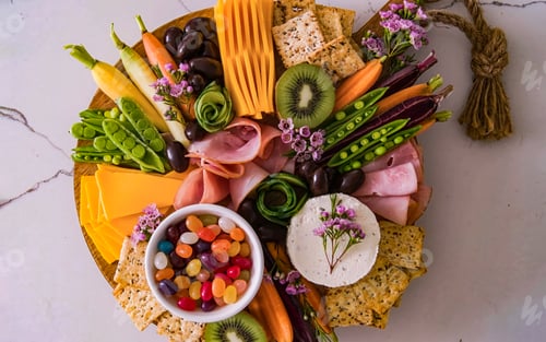 Preview: Cheese board served with fruits, vegetables, ham, crackers, sweets. Plate of cheese and snacks on wo