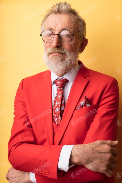 Preview: Senior experienced artist having tired sad eyes poses in red suit on yellow