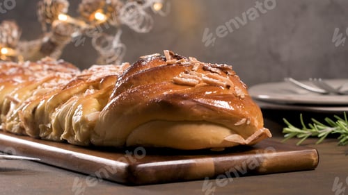 Preview: Homemade braided sweet Christmas bread with sliced almonds on a wooden board
