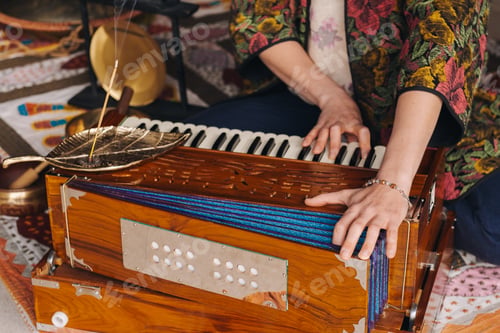 Preview: Hands of a woman sitting on the floor and playing the harmonium during the practice of kundalini