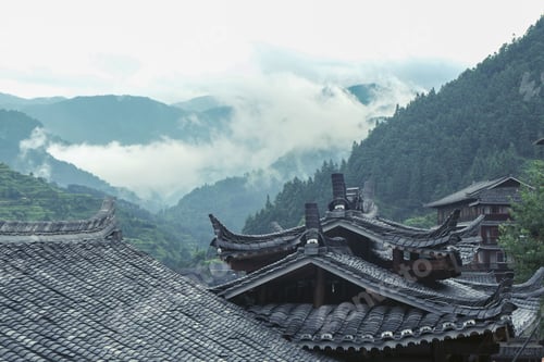 Preview: Traditional buildings in a Miao Village in Xijiang, Guizhou, China with mountains in a background