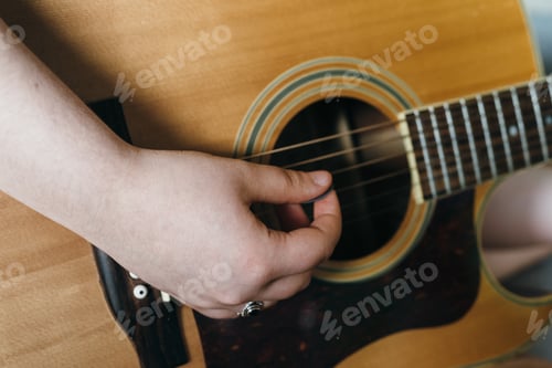 Preview: Young woman playing acoustic guitar at home